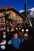 Menschen beim Après Ski vor einer Hütte unter blauem Himmel, St. Anton, Arlberg, Tirol, Österreich, Europa