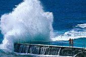 Two men standing at a seawater pool at the surge, Bondi Beach, Sydney, New South Wales, Australia
