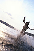 Woman running into the water of a lake