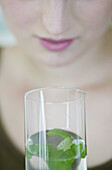 Girl breathing in air from glass with lemon balm leaves in water, Austria