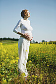 Pregnant woman standing in yellow field