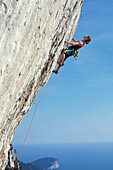 Female free climber scaling rock face, Muzzerone, Portovenere, Cinque Terre, Liguria, Italy