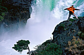 Man standing near a waterfall feeling the force of nature, Paine National Park, Patagonia, Argentina