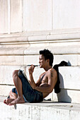 Junger Mann sonnt sich oben ohne am Königsplatz, München, Bayern, Deutschland
