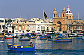 View of fishing boats at harbour and church, Marsaxlokk, Malta, Europe