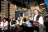 People in front of ski hut in the sunlight, Saalbach, Salzburger Land, Austria, Europe