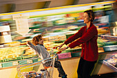 Woman pushing a toddler in a supermarket trolley, Supermarkt, People