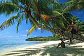 Couple sitting on the beach in the shade, Ile aux Nattes, Ste Marie, Madagascar, Indian Ocean