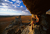 Woman sitting on a rock formation, La Fenetre, Isalo National Park, West Madagascar, Africa