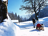Woman on a Winter walk with her children, children on a sledge, near Garmisch-Partenkirchen, Upper Bavaria, Bavaria, Germany