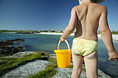 Child on the beach carrying a bucket, Akrasanden, Karmoy Island, Rogaland, Norway