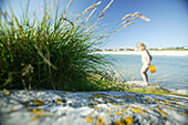 Child on the beach carrying a bucket, Akrasanden, Karmoy Island, Rogaland, Norway