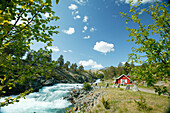Small red house at river near Grotli, Oppland, Norway
