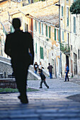 Man walking down a steep path in the old part of town, Medieval aqueduct, Aquaedotto, Perugia, Umbria Italy