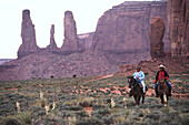 Two people on horseback near the Three Sisters, Monument Valley, Arizona, Utah, USA