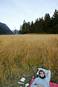 Young man lying in grass near Weitsee, Reit im Winkl, Bavaria, Germany