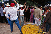 Menschen tanzen neben grosser Paellapfanne, Romeria de San Isidro, Nerja, Costa del Sol, Provinz Malaga, Andalusien, Spanien, Europa