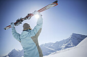 Woman lifting skis, Hohe Mut und Gaiskogel in the backround, Kuehtai, Tyrol, Austria