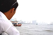 Man looking at Huangpu river and ferry, Shanghai, China, Asia