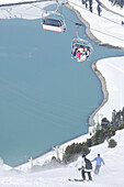 Skiers on slope and chair lift, reservoir in background, Kuhtai, Tyrol, Austria