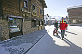 Father pulling two children on a sledge through the pedestrian zone, Livigno, Italy