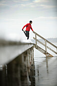 Young man streching leg at jetty