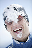 Young man with snow in his face, laughing