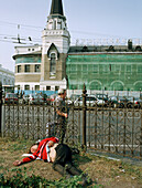 Ein Mann liegt auf dem Boden, im Hintergrund der Yaroslaw Bahnhof, Moskau, Russland