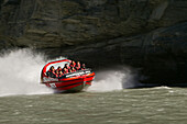 Menschen fahren ein Jetboot auf dem Shotover Fluss, Queenstown, Central Otago, Südinsel, Neuseeland, Ozeanien