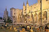 Menschen sitzen vor dem Papstpalast in der Abendsonne, Place de Palais, Avignon, Provence, Frankreich