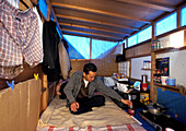 Homeless, living boxes in Tokyo, Japan, Man in his self made plywood hut on the Sumida River banks Obdachlose, notduerftige Schutzbauten, Pappkarton-Architektur, Plastikplanen, Slum, Obdachlosigkeit, Randgruppe, Astronomical high rents have caused the hom