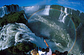 Tourists on a lookout platform watching the Iguazú waterfalls, Brazil, South America