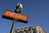 Metro sign with a facade of a builidng, Paris, France