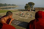 Monks watch football match from U Bein bridge, Moenche beobachten Fussballspiel von der U Bein Bruecke, Amarapura bei Mandalay