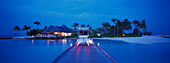 Holzsteg und Four Seasons Resort unter Palmen am Abend, Kuda Hurra, Malediven, Indischer Ozean