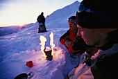 Group of people sitting around a camping stove after a snowshowing tour, Trekking, Nebelhorn, Allgaeuer Alps, Allgaeu, Germany