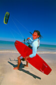 Young man on beach with kiteboarding gear, ready for start