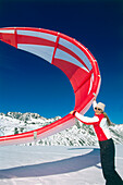 Young woman holding kite, kiteboarding in snow, Lermoos, Lechtaler Alpen, Tyrol, Austria