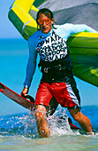 Man kiteboarding, holding kite and board
