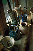 Tools and clay pots on a ledge of a pottery