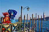 Masked people in disguise on a jetty in the sunlight, Venice, Italy, Europe