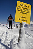 Skier passing warning sign, leaving safety slope, Nebelhorn, Oberstdorf, Bavaria