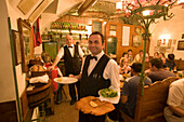 Waiter serving giant Wiener Schnitzel at Restaurant Figlmüller, Vienna, Austria