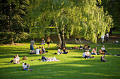 People relaxing on grass of Burggarten, Alte Hofburg, Vienna, Austria