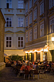 People sitting in the open-air area of the restaurant Kuchldragoner, Bermuda Triangle in the near of Ruprechtskirche in the evening, Vienna, Austria