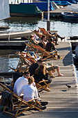 People sitting on deck chairs, People sitting on deck chairs on a jetty of Bodo's Bootssteg at lake Alster, Hamburg, Germany