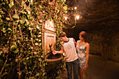 Couple near wine fountain in Buda Castle Labyrinth, Couple next to the wine fountain in Buda Castle Labyrinth, Buda, Budapest, Hungary