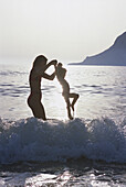 Mother and daughter in the water, jumping