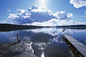 Man jumping off jetty into lake, side view