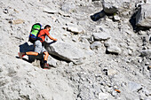 Man scrambling on a steep path on loose ground, Path to Forno hut, SAC, Swiss Alpine Club, Bergell, Bregaglia, Graubuenden, Grisons, Switzerland, Alps